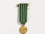 a close up of a medal on a white surface with a green ribbon