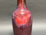 a red vase sitting on a table with a gray background