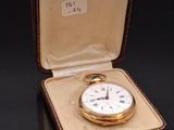 a gold pocket watch in a case on a black surface