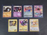 Plusieurs cartes Pokémon sont alignées sur une surface noire