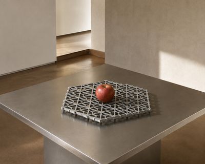 une table en métal sur laquelle est posée une pomme rouge