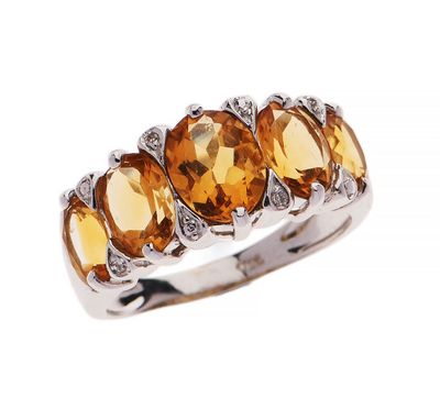 un gros plan d'une bague à trois pierres sur fond blanc