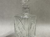 flacon de parfum en verre transparent muni d'un bouchon en verre, sur fond blanc