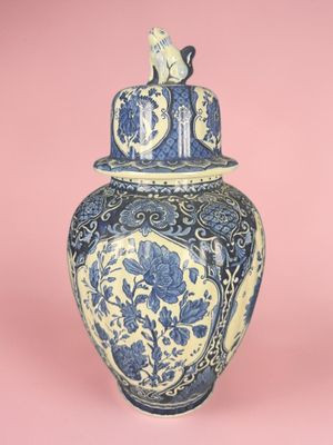 un vase bleu et blanc surmonté d'un chat
