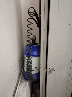 un vaporisateur bleu et blanc et un tuyau noir et blanc dans un coin de la pièce