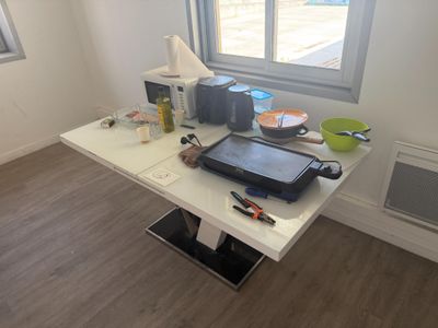 une table blanche sur laquelle est posée une casserole, dans une pièce