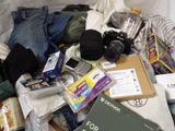 a pile of items on a bed with a camera and a book