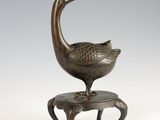 bronze sculpture of a bird sitting on a small stool