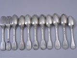 six spoons and a fork are lined up on a table