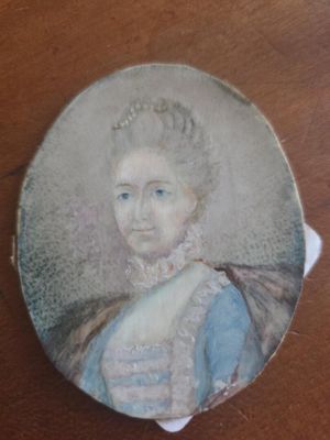 an old picture of a woman in a blue dress on a wooden table