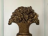 un vase en or avec des fleurs accroché au mur de la pièce