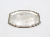 an antique silver tray with a decorative edge on a white surface