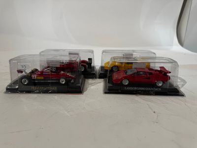 two red toy cars are in a clear case on a white surface