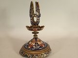 a gold and blue candle holder with a bird on it