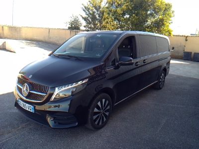 La camionnette noire est garée sur le parking près des arbres.
