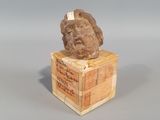 une statue représentant un homme assis sur une caisse en bois