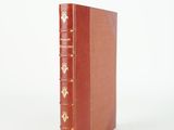 an old red book sitting on top of a white surface