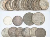 an assortment of silver and silver coins on a white surface