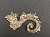 un gros plan d'une broche en forme de dragon doré posée sur une surface noire