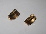 two pieces of gold plated metal on a white surface