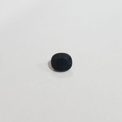 une petite pierre noire posée sur une surface blanche