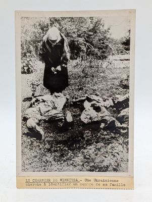 une vieille photo montrant une femme debout près d'animaux morts dans un champ