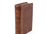 an old brown book sitting on top of a white surface