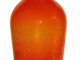 an orange glass vase that is sitting on a white surface