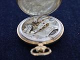 a small silver pocket watch sitting on a blue surface
