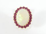 un gros plan d'une bague en oplite blanche et rubis posée sur une surface blanche