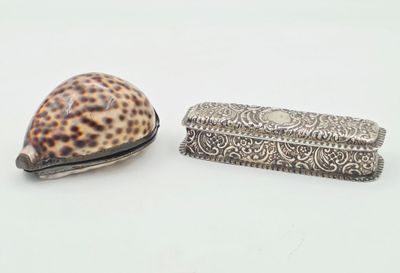 un coquillage et une boîte en argent posés sur une surface blanche