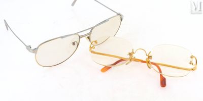 une paire de lunettes à monture dorée et à verres transparents posée sur une surface blanche