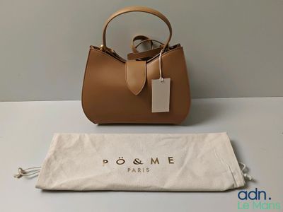 a brown purse sitting on top of a white table next to a bag
