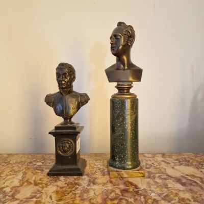 une paire de bustes en bronze représentant une femme et un homme, posés sur des socles en marbre