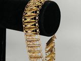a close up of a gold bracelet on a black stand