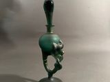 un petit vase vert muni d'une anse noire, posé sur une table
