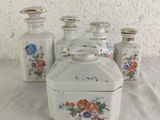 three small white jars with flowers on them on a table