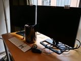 deux écrans et un clavier posés sur un bureau devant une fenêtre