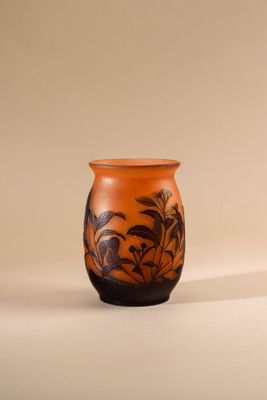 a small orange vase with a black design on it
