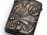 a close up of a silver cigarette case on a white surface