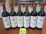 six bouteilles de vin posées sur une table, avec une étiquette de prix devant chacune d'elles