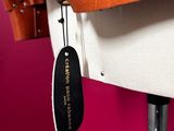 brown leather handbag hanging on a mannequin with a tag