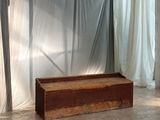 un banc en bois devant un rideau, dans une pièce