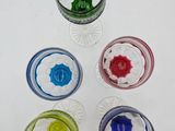 six different colored glasses are arranged in a row on a white surface