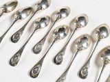 six silver spoons are lined up in a row on a white surface
