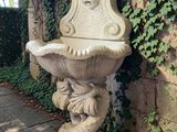 une statue représentant une femme assise sur une fontaine au milieu d'un jardin