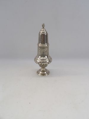 une salière ancienne en argent posée sur une surface blanche