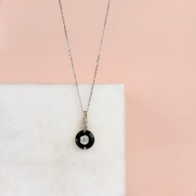 a black and white diamond pendant on a white marble slab