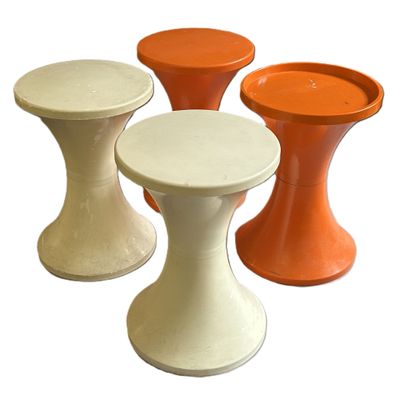 trois tabourets de couleurs différentes, placés les uns à côté des autres sur une surface blanche