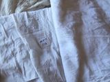 une couverture blanche posée sur un lit, sur laquelle est accrochée une étiquette